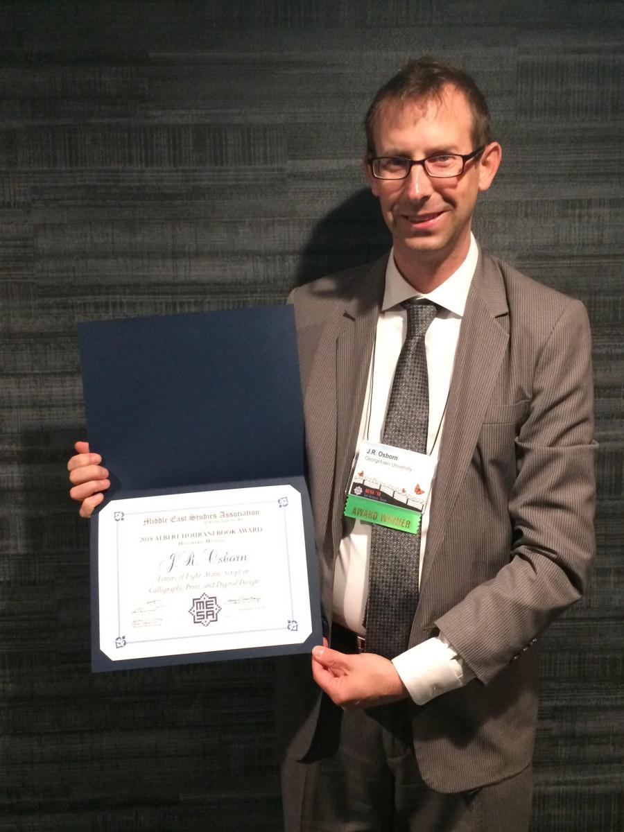 Professor Osborn holding the award certificate of recognition