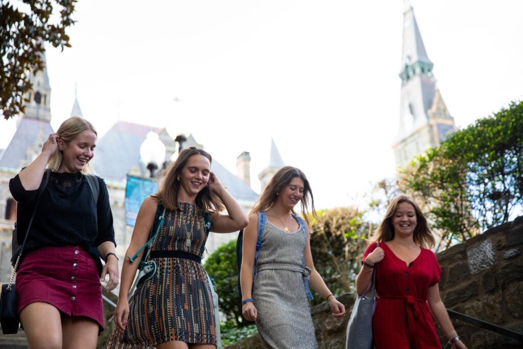 four students walking with Healy Hall in the background.