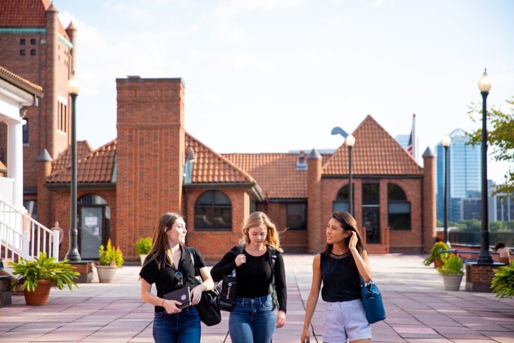 Three students walking through the Car Barn courtyard.