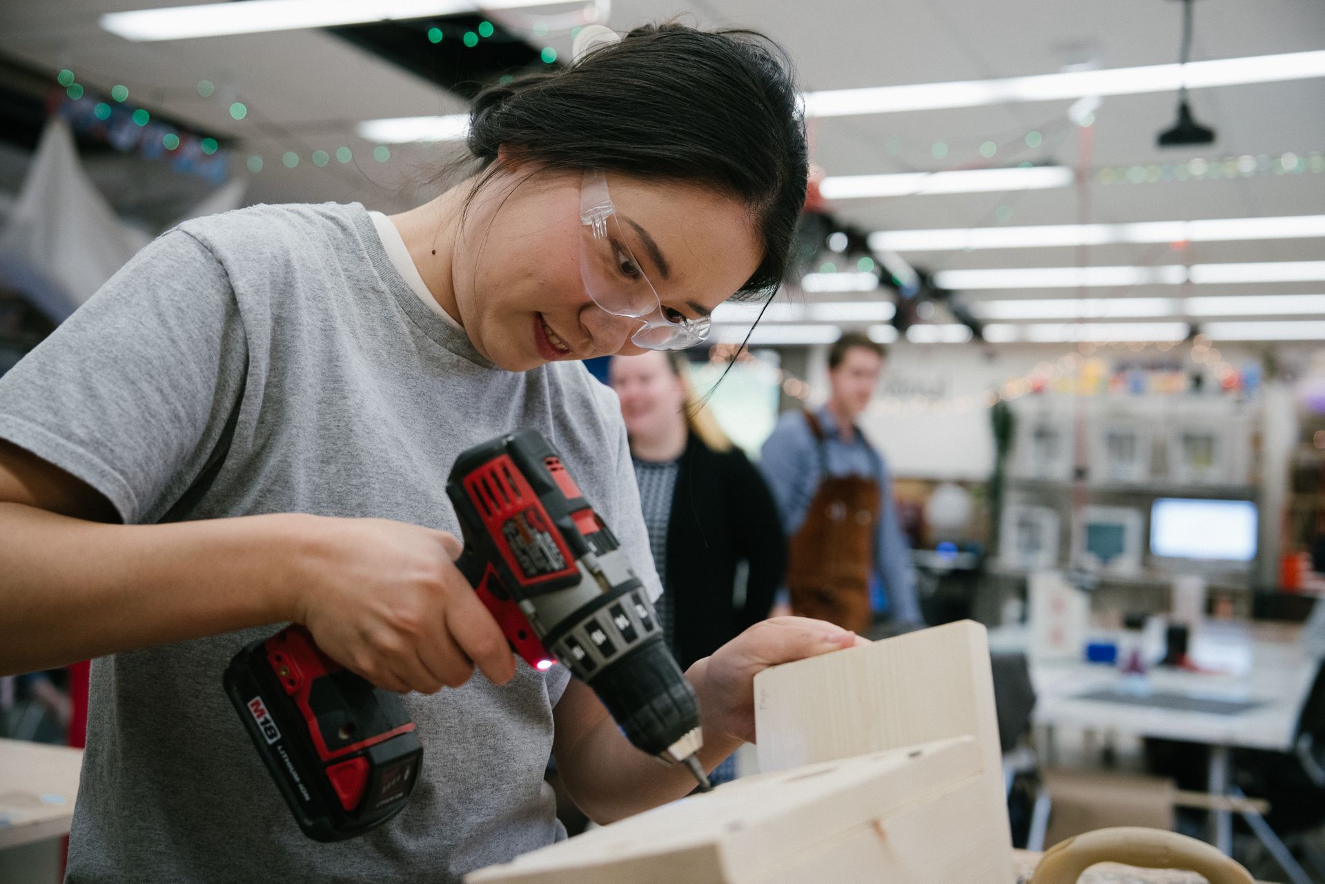 A student uses a drill in the maker lab.